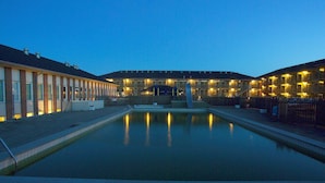 A hotel with a swimming pool, multiple balconies, and a fenced courtyard. - 4 Person Holiday Home on a Holiday Park in Fano (Fano)