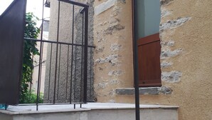 A building with a stone facade, a wooden door, and a metal railing. - Small artist's house (Saint-Étienne-les-Orgues)
