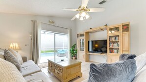 Una sala de estar con sofá, una mesa de centro, televisor y armarios de madera.