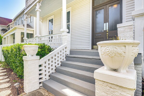 A house with a front porch, a staircase, and a large decorative urn. - Walk to Strand District: Historic Galveston Home (Galveston)