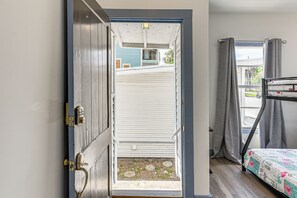 A room with a bunk bed, a door leading to an outdoor area, and a view of a building outside. - 1 Mi to Pleasure Pier: Golden-age Getaway! (Galveston)