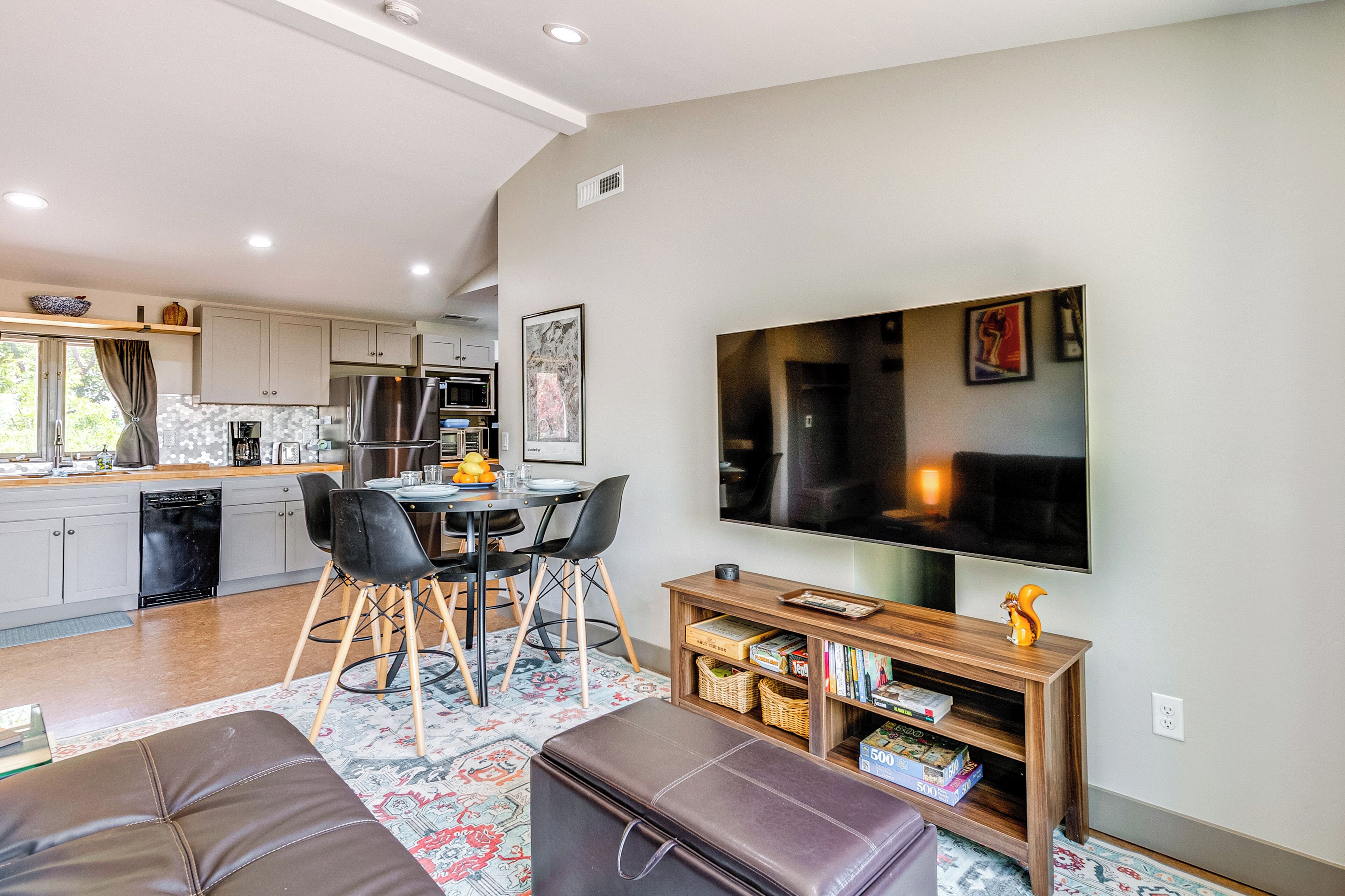 A modern kitchen with a dining area, a flat-screen TV, and a bookshelf.