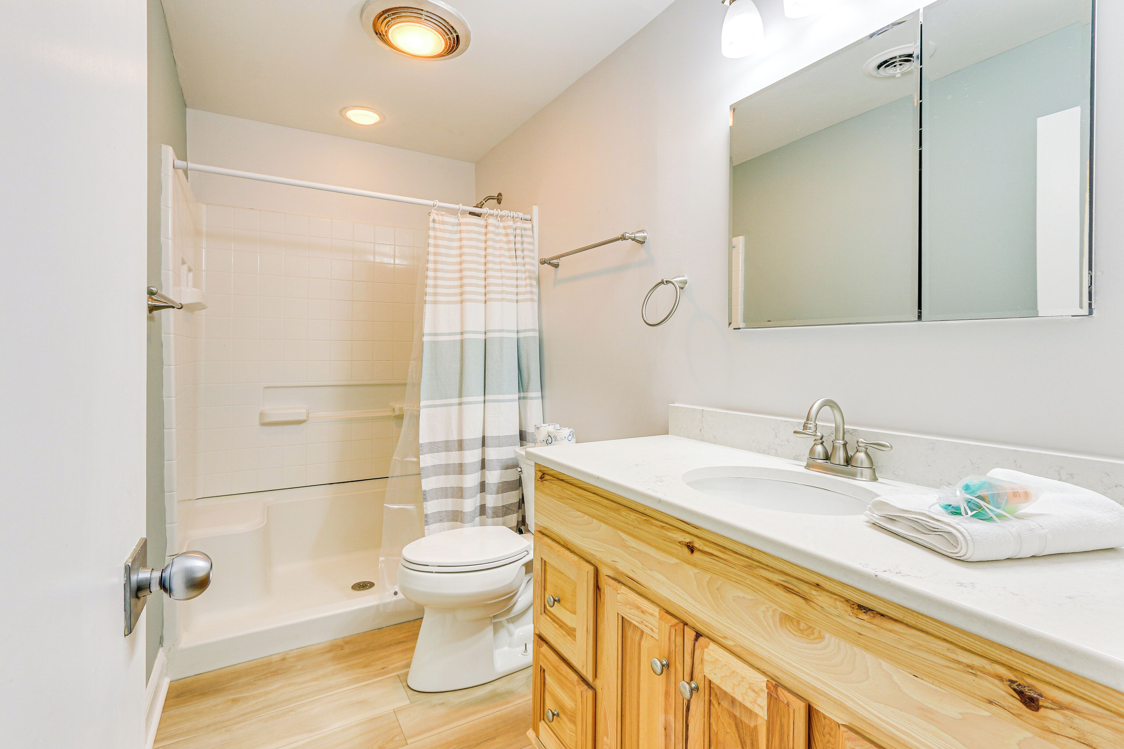 A modern bathroom with a shower, toilet, vanity, and a large mirror.