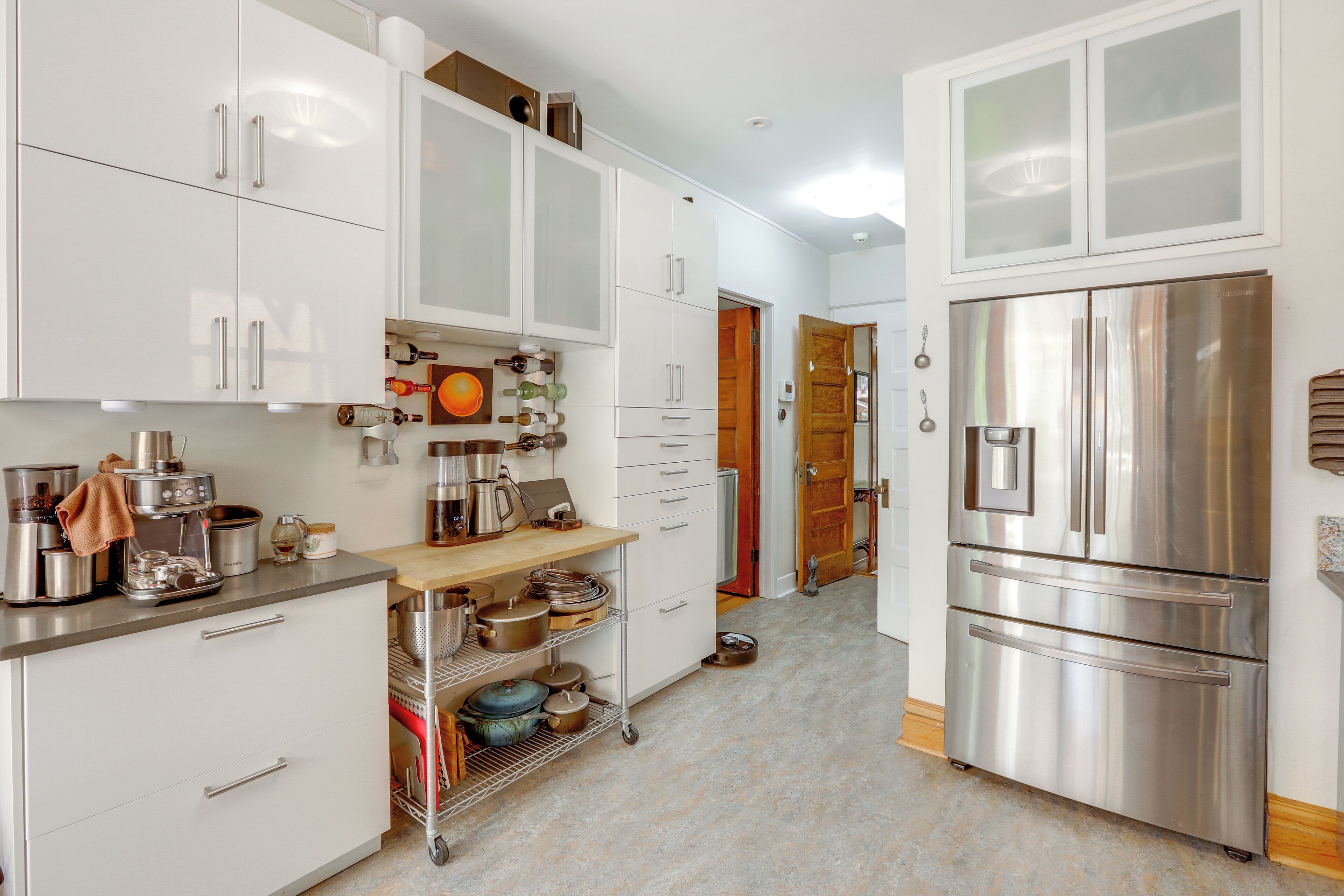 A modern kitchen with white cabinets, stainless steel appliances, and a wooden countertop.