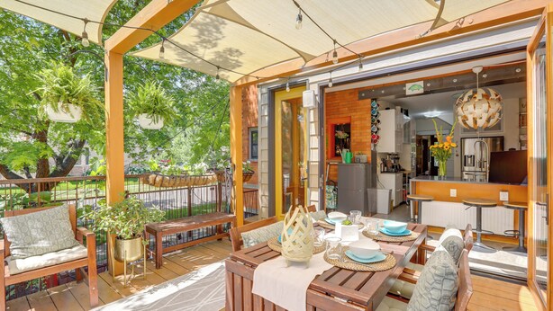 An outdoor patio with wooden furniture, a dining table set for two, and hanging plants. - Walk to Denver Zoo: City Park Getaway w/ Garden (Denver)