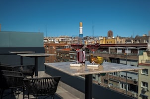 Une terrasse sur le toit, avec une table dressée pour deux personnes, une bouteille de vin et deux verres de vin rouge.