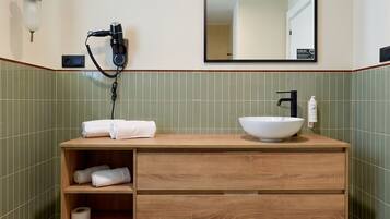 A bathroom with a wooden vanity, a white sink, a hairdryer, and a mirror.