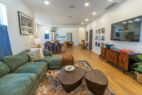 A modern living room with a green sofa, a coffee table, and a dining area in the background. - Bold & Fun Getaway Steps from Train & Beach (Michigan City)