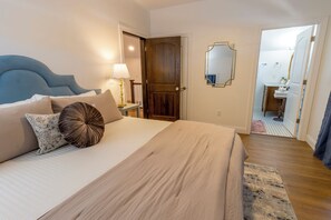 A bedroom with a bed, bedside table, lamp, and a door leading to a bathroom. - Bold & Fun Getaway Steps from Train & Beach (Michigan City)