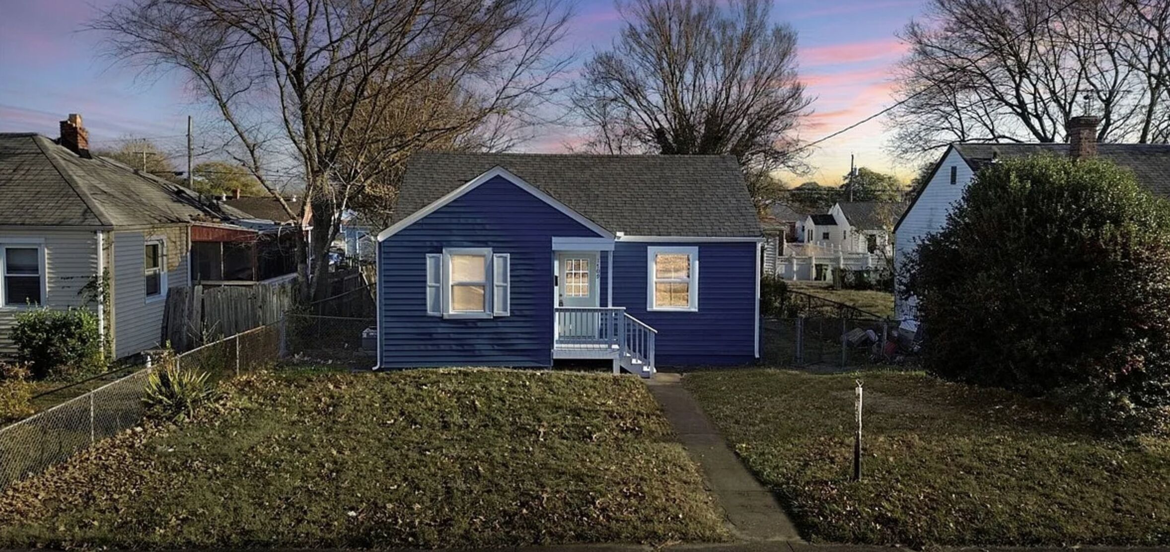 Une petite maison de plain-pied avec un porche à l’avant et un chemin menant à l’entrée.