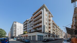 Un edificio residencial de varios pisos con balcones, garaje y cielo despejado.