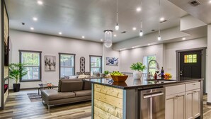 A modern kitchen with a central island, stainless steel appliances, and a dining area with a sofa. - Bearfoot Getaway - New Lux Cabin Hot Tub Pool (Gatlinburg)