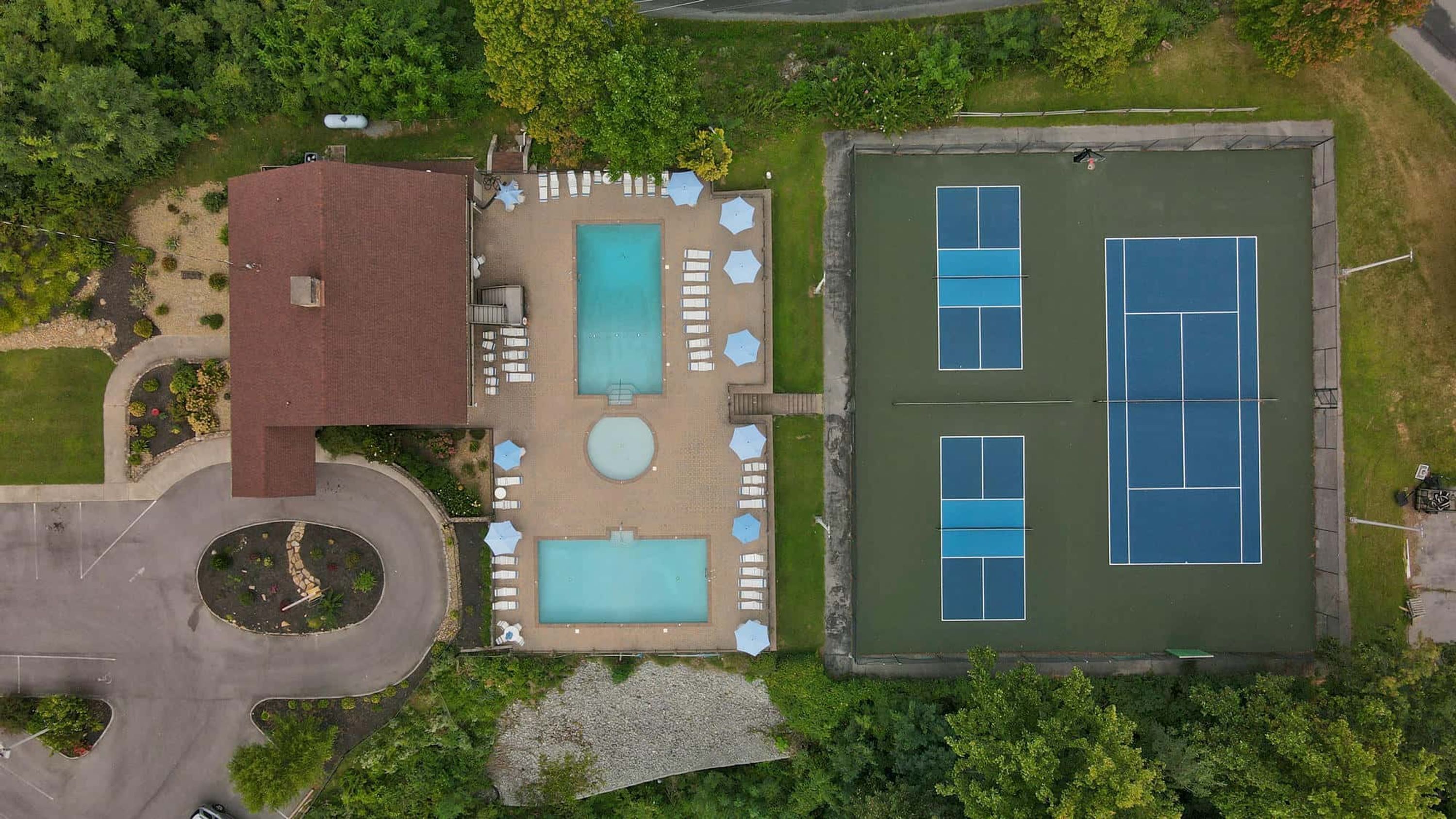 A property with a swimming pool, tennis courts, and a covered patio area.