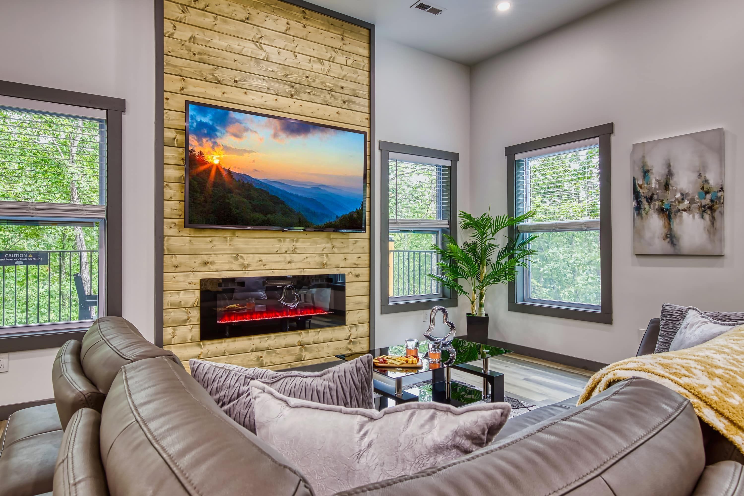 A modern living room with a fireplace, a large flat-screen TV, and a comfortable sofa.