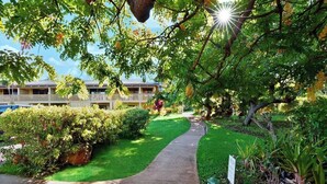 Un camino que lleva a un edificio con patio cercado y abundante vegetación.