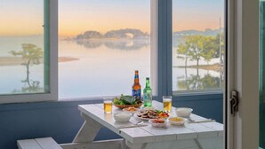 A table with food and drinks, a window with a view of a lake and trees, and a door. - Daebudo Aladdin Pension (Ansan)