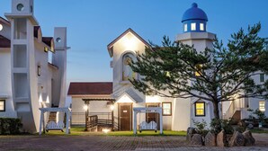 A building with a prominent tower and a smaller structure with a dome, both lit up. - Daebudo Aladdin Pension (Ansan)
