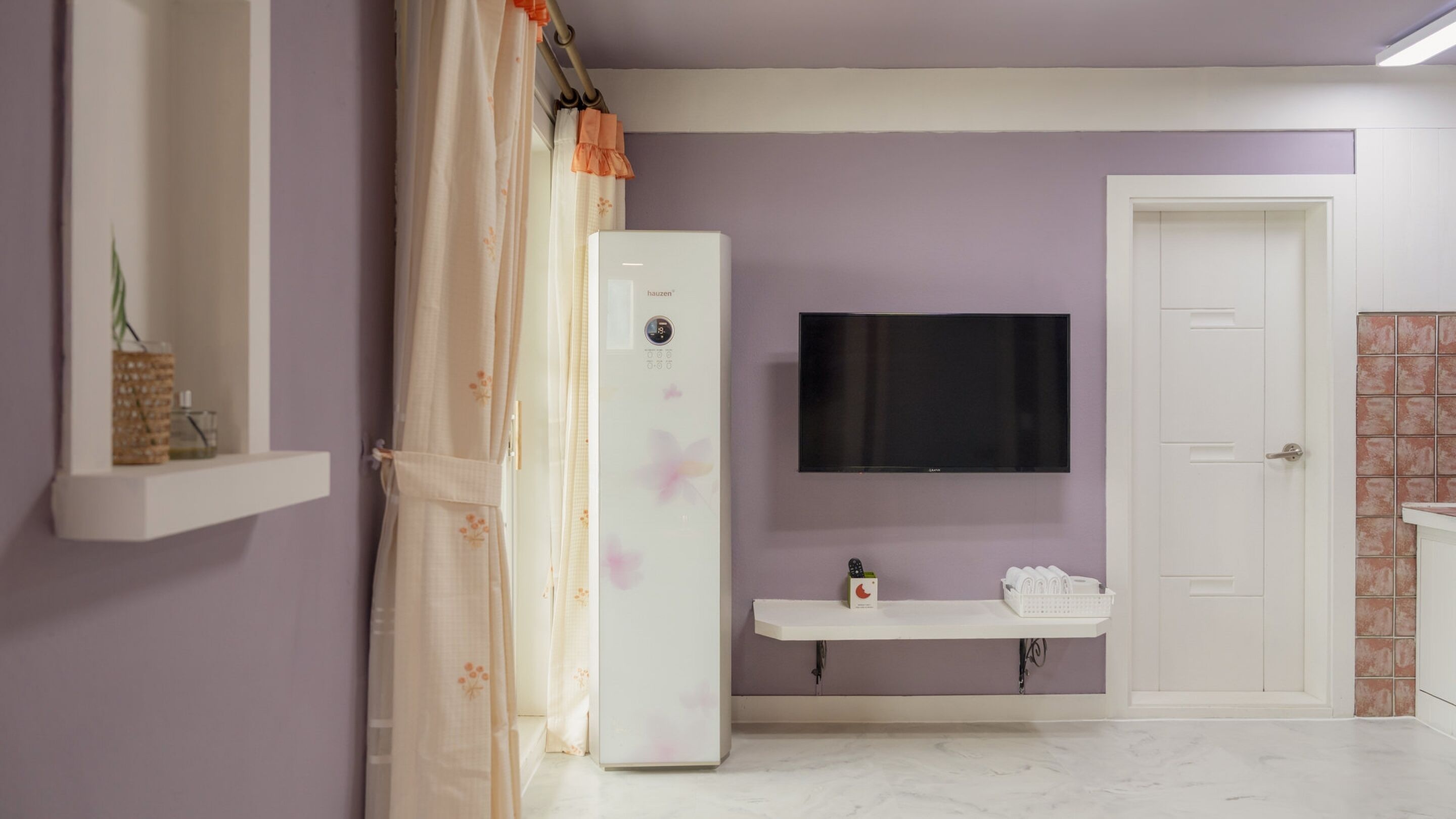 Une salle de bain équipée d’une douche, de toilettes, d’un lavabo et d’un téléviseur fixé au mur.