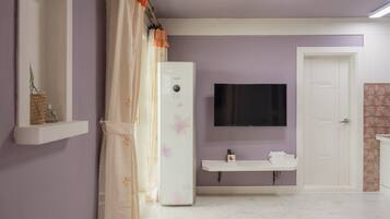 Une salle de bain équipée d’une douche, de toilettes, d’un lavabo et d’un téléviseur fixé au mur.