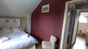 Un dormitorio con cama, una silla, una mesita de noche y un cuadro en la pared.