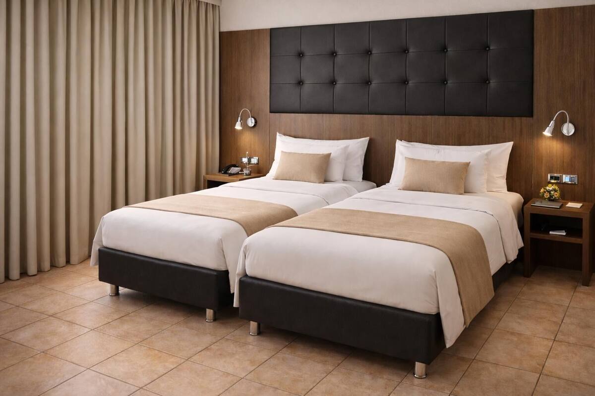 A double bed with a dark headboard, two bedside tables with lamps, and a curtain to the left.