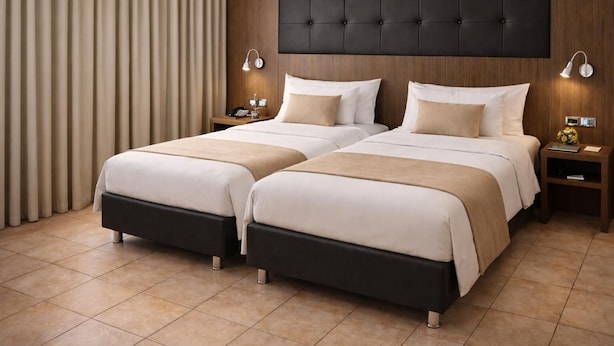 A double bed with a dark headboard, two bedside tables with lamps, and a curtain to the left.