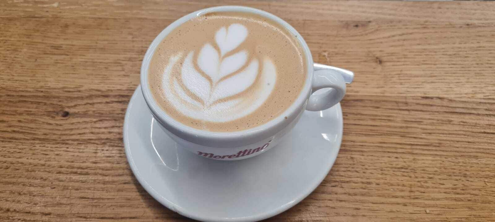Una taza de café con arte de latte sobre una mesa de madera.