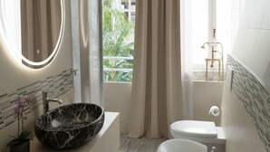 A modern bathroom with a marble sink, a freestanding bathtub, and a toilet.
