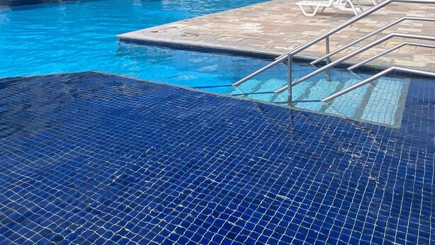 Ein Schwimmbecken mit Liegestühlen und einem Gebäude im Hintergrund.