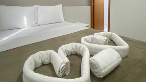 Ein Hotelzimmer mit einem Bett, zwei zusammengerollten Handtüchern und einer Klimaanlage.