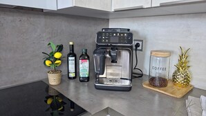 A kitchen counter with a coffee maker, a jar of coffee beans, a bottle of olive oil, and a decorative pineapple. - ErzZeit - Vacation with a vision (Schwarzenberg/Erzgebirge)