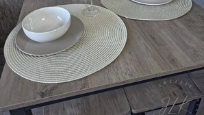 A dining table set with white bowls and glasses on woven placemats, against a textured wall. - ErzZeit - Vacation with a vision (Schwarzenberg/Erzgebirge)