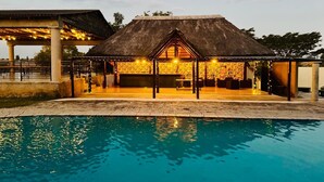 A poolside area with a thatched-roof structure, a reception desk, and a covered seating area. - Dwaleni Farm Lodge (Matsapha)