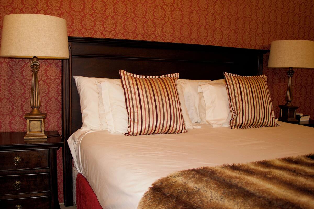 A neatly made bed with striped pillows, a wooden headboard, and two bedside lamps.