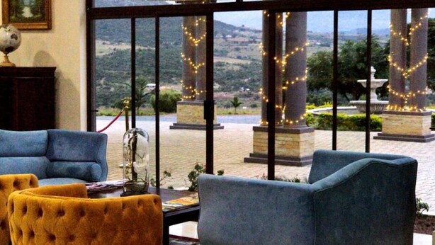 A lobby with two blue armchairs, a yellow armchair, and a globe on a stand. - Dwaleni Farm Lodge (Matsapha)