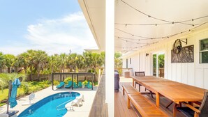A wooden deck with a pool, outdoor seating, and a dining area with a table and chairs. - Spacious Pensacola Beach Retreat with Private Pool & Game Room | Sleeps 15 (Pensacola Beach)