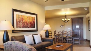 A living room with a sofa, armchair, and coffee table, a dining area with wooden chairs and a table, and a framed painting on the wall. - 1-bedroom condo Grand Lodge @ Peak 7 in fantastic Breckenridge with fitness room (Breckenridge)