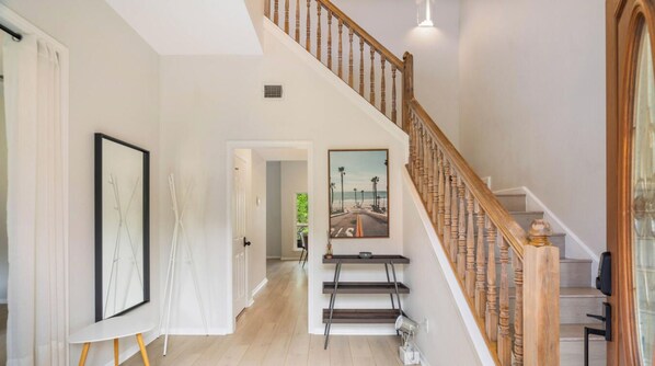 A spacious hallway with a wooden staircase, a framed picture on the wall, and a door leading to another room. - Skyflower Dr xxxxxxx (Austin)