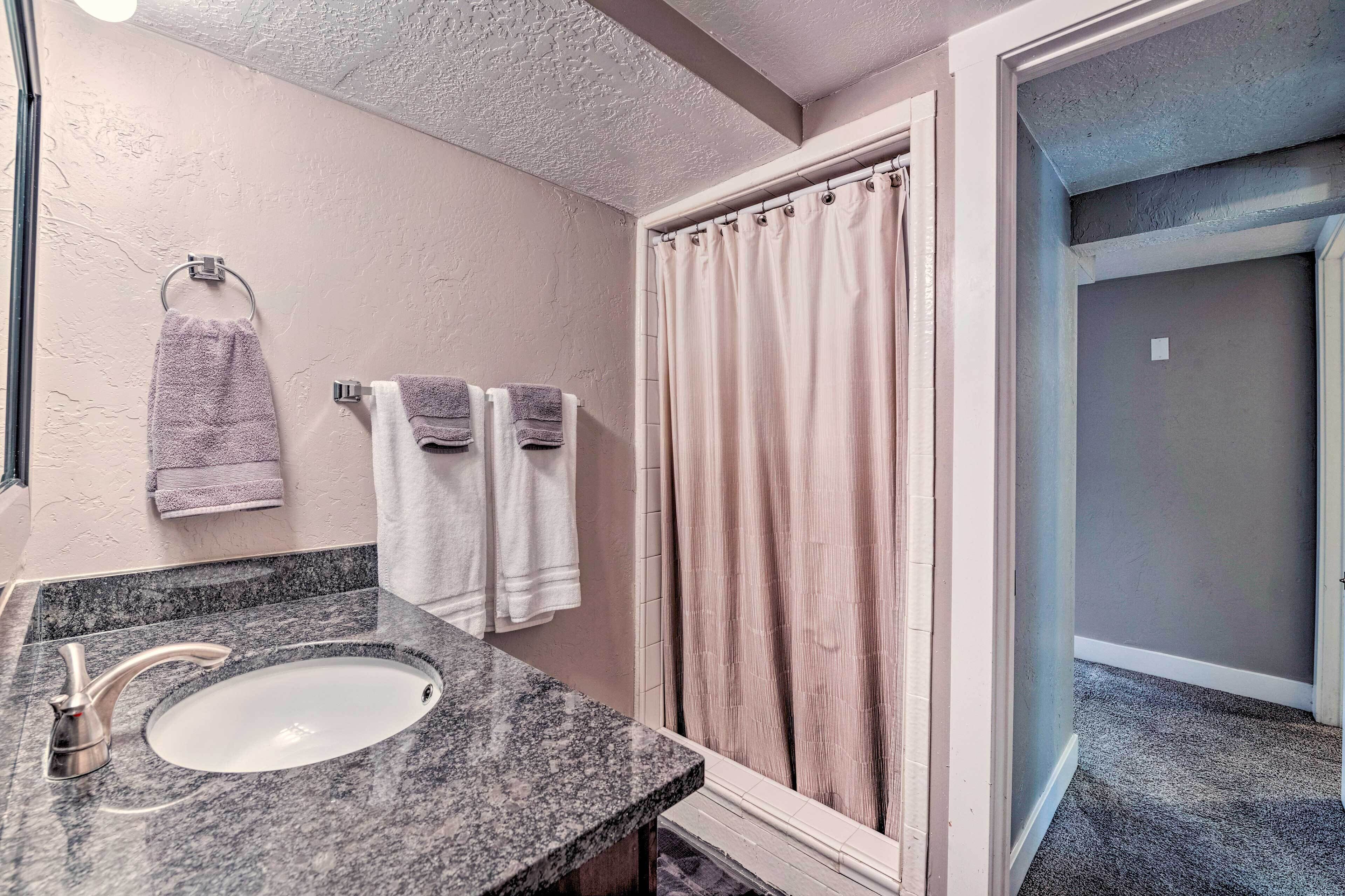 Une salle de bain avec un lavabo, deux serviettes et un rideau de douche.