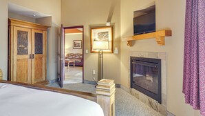 Een hotelkamer met een bed, een houten garderobe, een open haard en een televisie erboven.