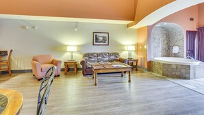Een woonkamer met een bank, fauteuils, een salontafel en een wand met stenen badkuip.