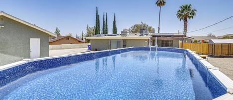 Una piscina rectangular con borde de azulejos, rodeada por una terraza de madera.