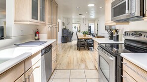A modern kitchen with wooden cabinets, stainless steel appliances, and a central island with seating. - 9 Mi to Joshua Tree NP: Yucca Valley Home w/ Pool (Yucca Valley)