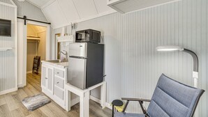 Une cuisine compacte équipée d’un réfrigérateur, d’un four à micro-ondes et d’un évier. On y trouve une chaise et un petit tapis.