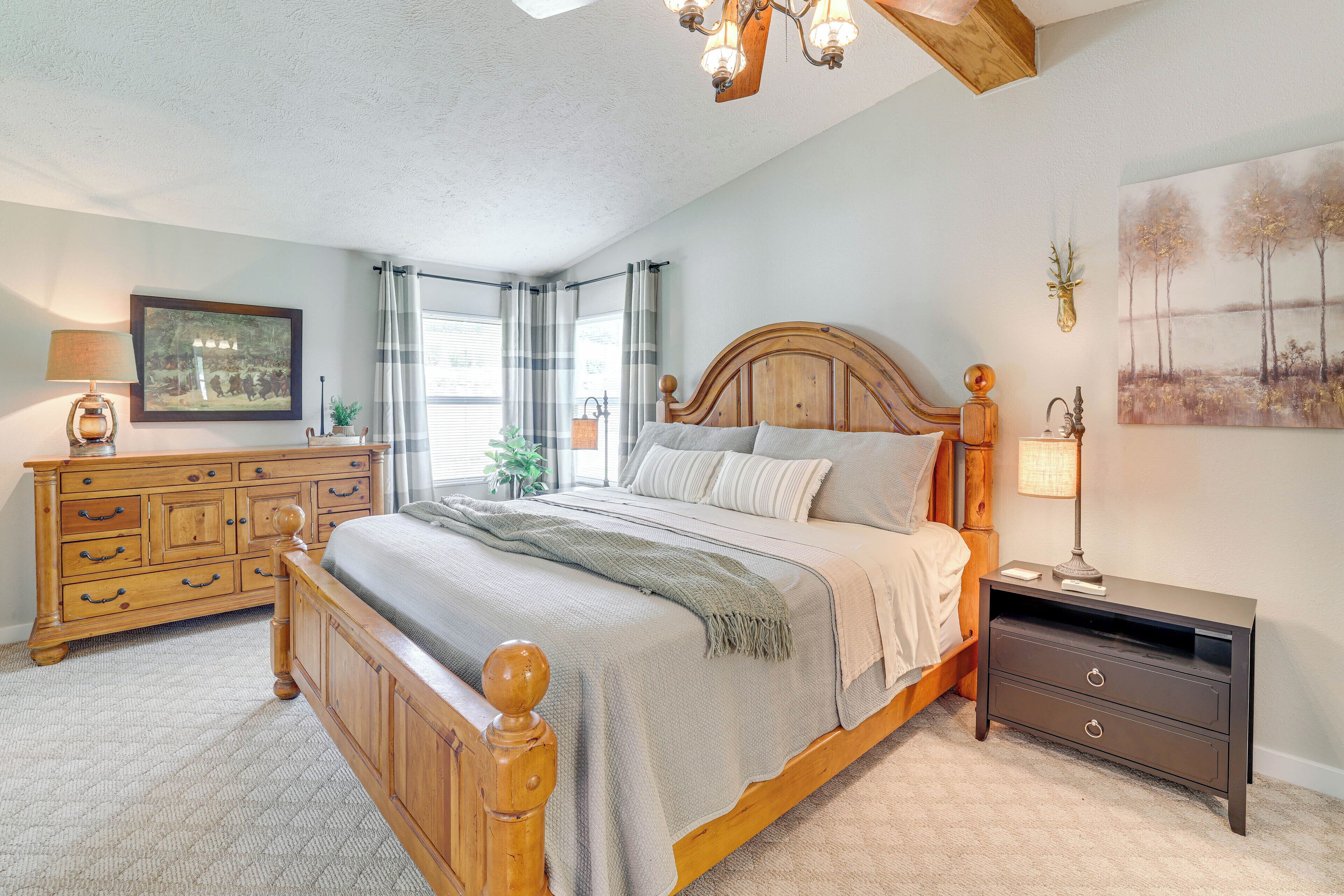 A bedroom with a wooden bed, a nightstand, a dresser, and a painting on the wall.