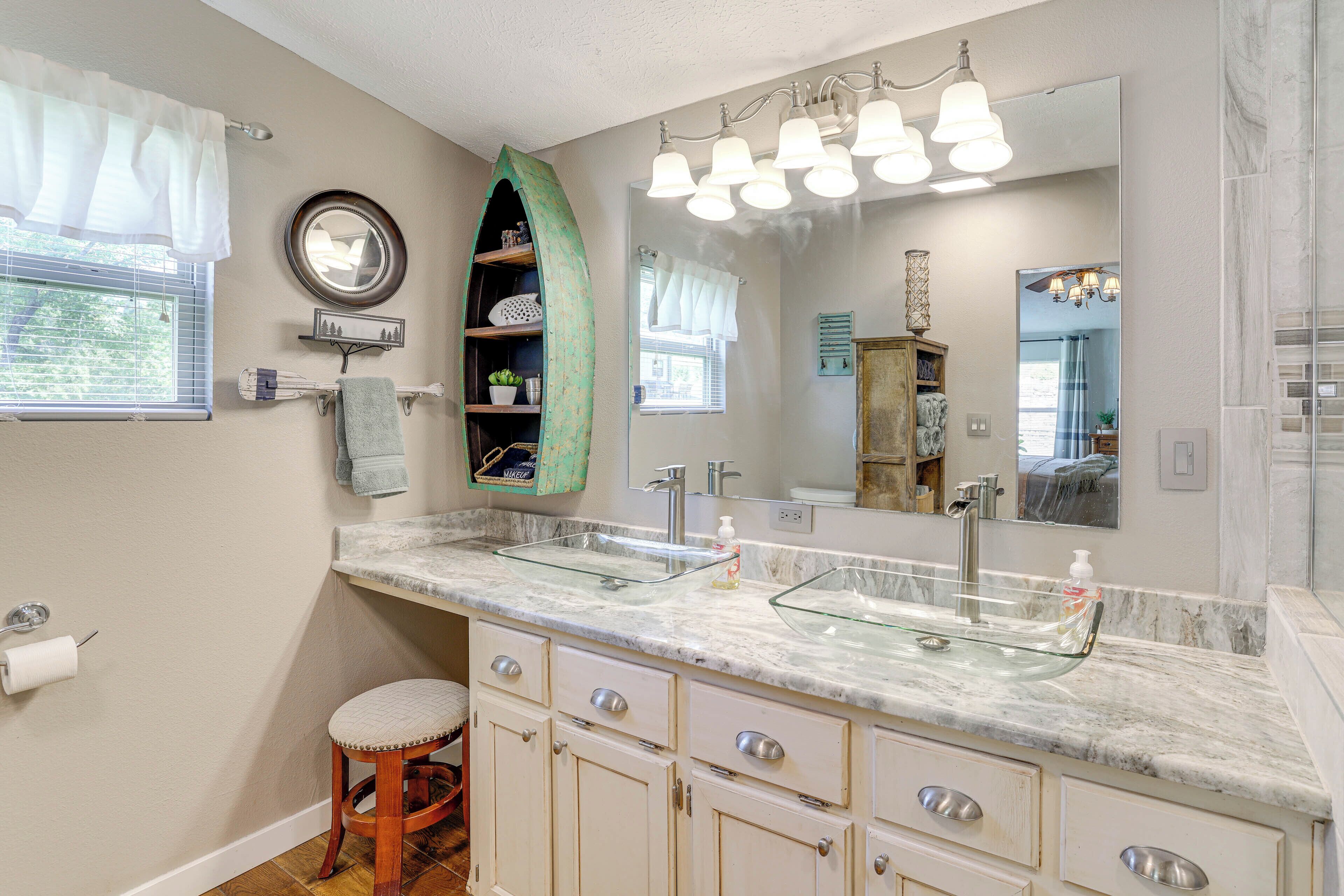 A bathroom with two sinks, a vanity with drawers, a mirror, and a window with curtains.