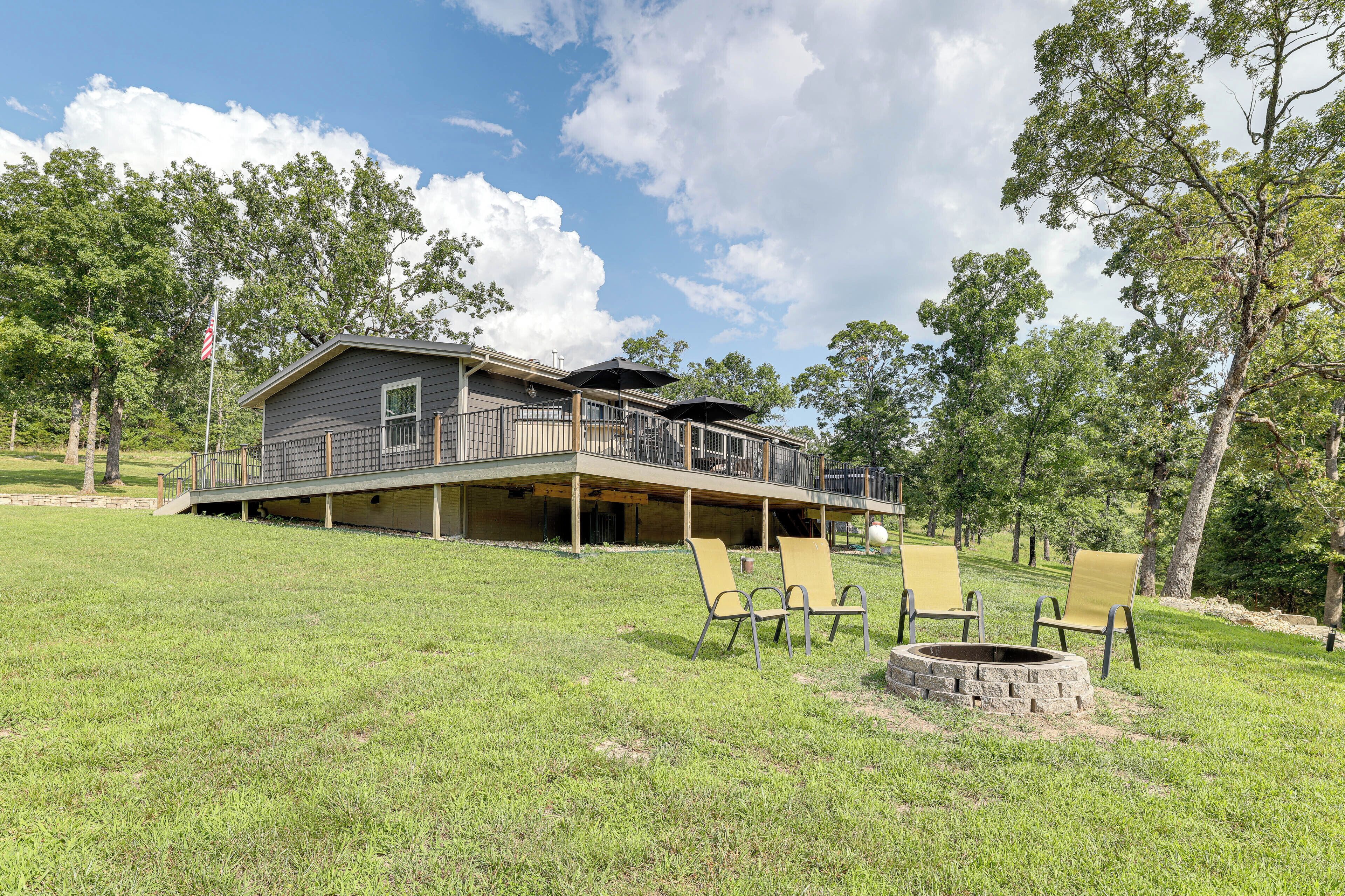 A two-story house with a balcony, a fire pit, and outdoor seating.