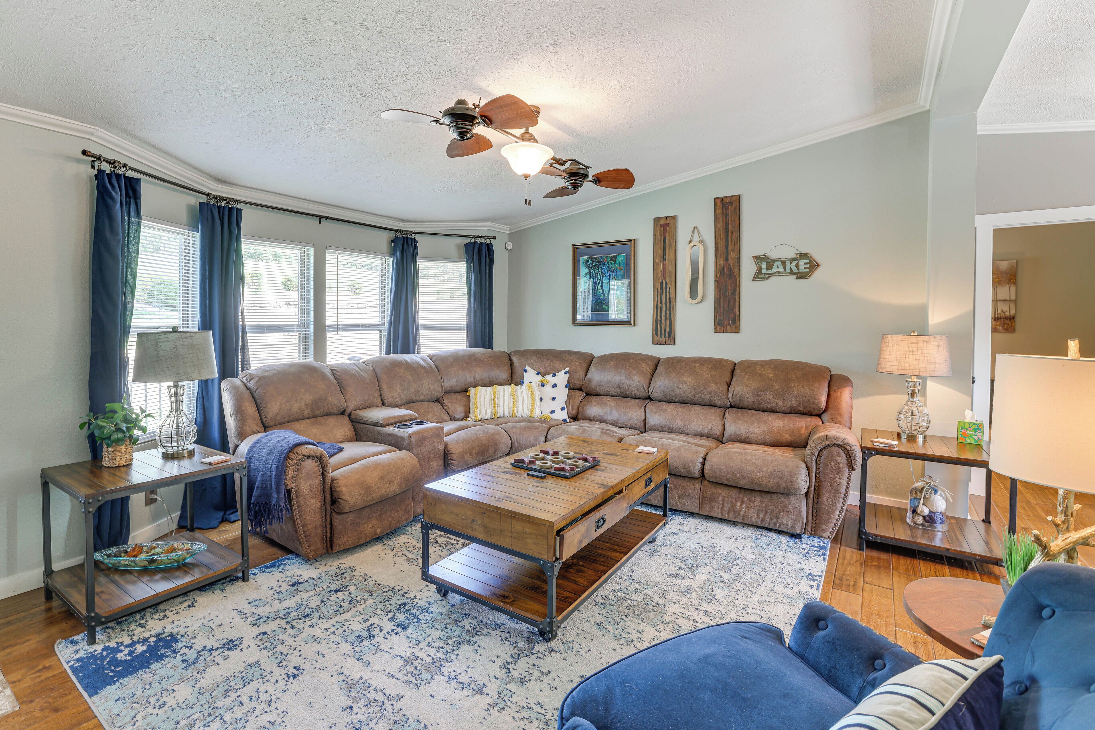 A living room with a sectional sofa, a coffee table, a side table, and a ceiling fan.