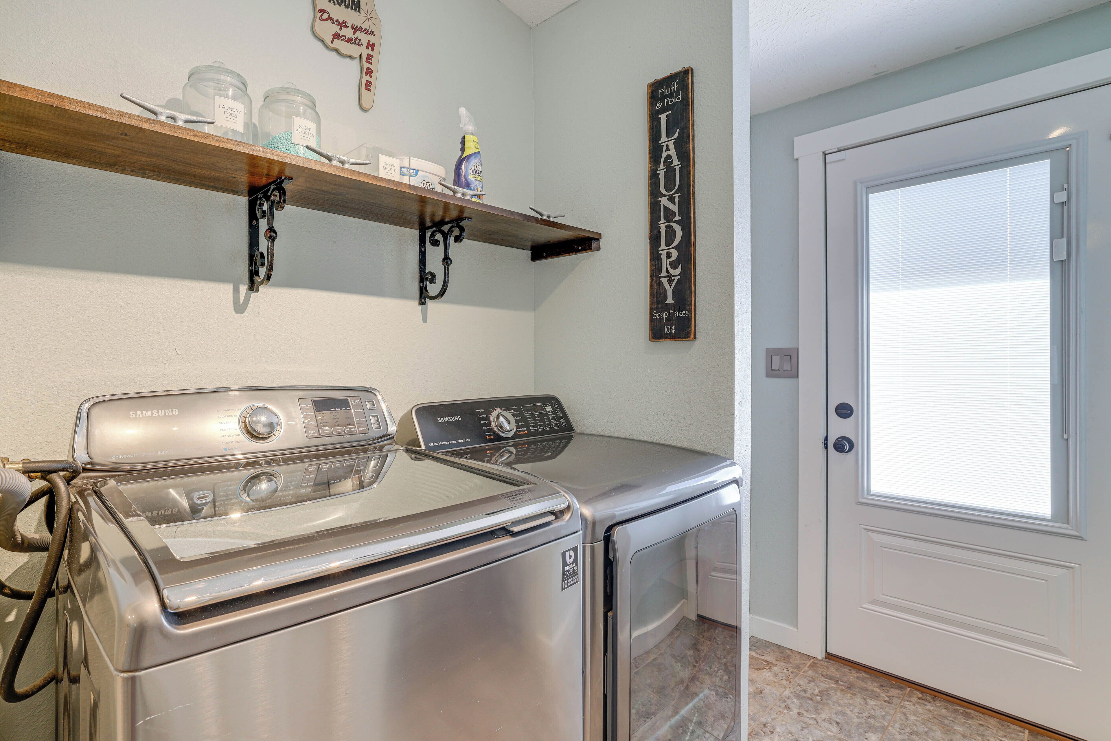 A laundry room with a Samsung washer and dryer, a shelf with cleaning supplies, and a sign that reads "Laundry."