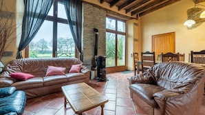 Ein gemütliches Wohnzimmer mit Ledersofas, einem Holztisch und einem Kamin aus Stein.
